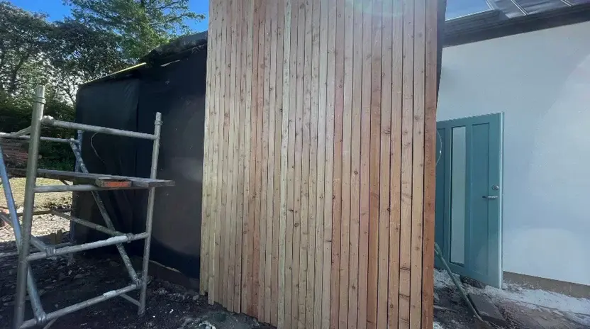 Vertical timber cladding meeting a rendered extension wall