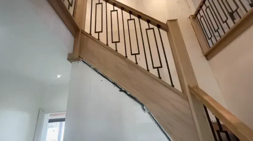 A staircase and landing balustrade with a timber handrail and decorative metal balusters